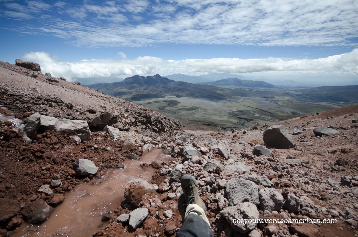 The author sits at the base of the glacier as ice cold water runs by and enjoys the view; Cotopaxi National Park, Ecuador | ©Angela Drake