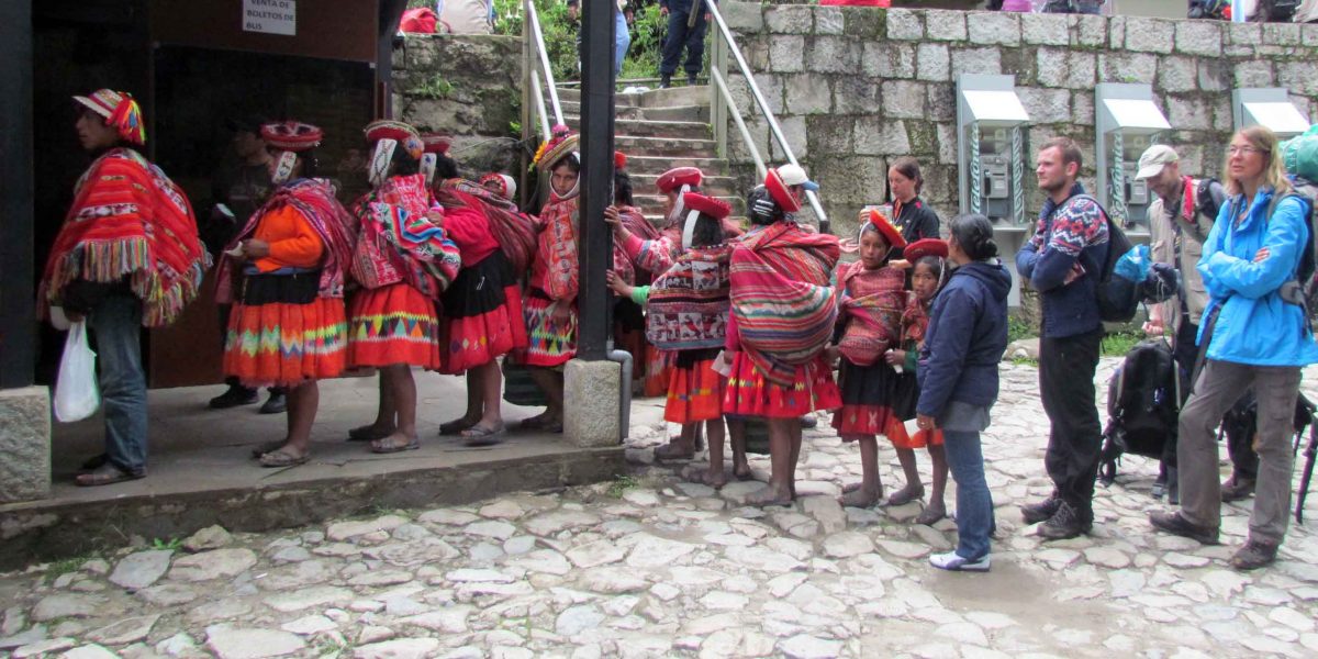 Quechua women and Western tourists waiting for the bus to Agua Calientes