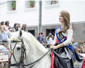 Woman wearing a sash and riding a white horse