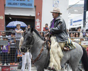 A man dressed in gaucho style, a working outfit that includes chaps made of alpaca hide on a charcoal gray horse