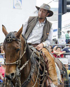 Working man on horse wears leather vest, chaps and hat