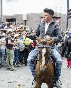 A young man appears to big for his small mount, a brown pony with white blaze