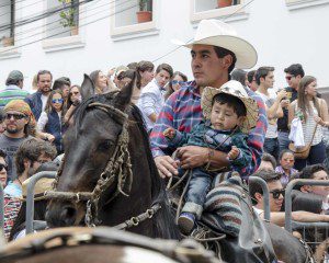 A father holds his infant son while riding on a black horse