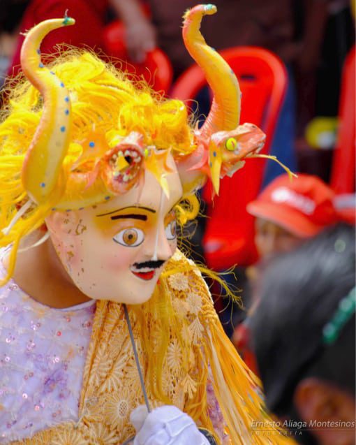Una china diabla trae una máscara con cuernos amarillos gigantes y cabello amarillo brillante