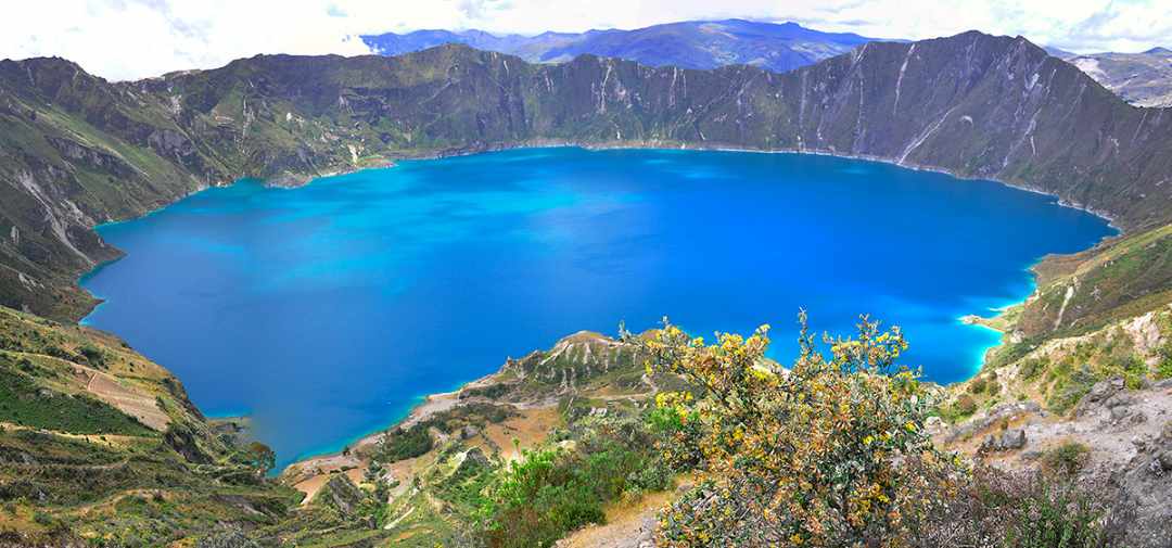 Brillante lago cráter azul rodeado de montañas verdes