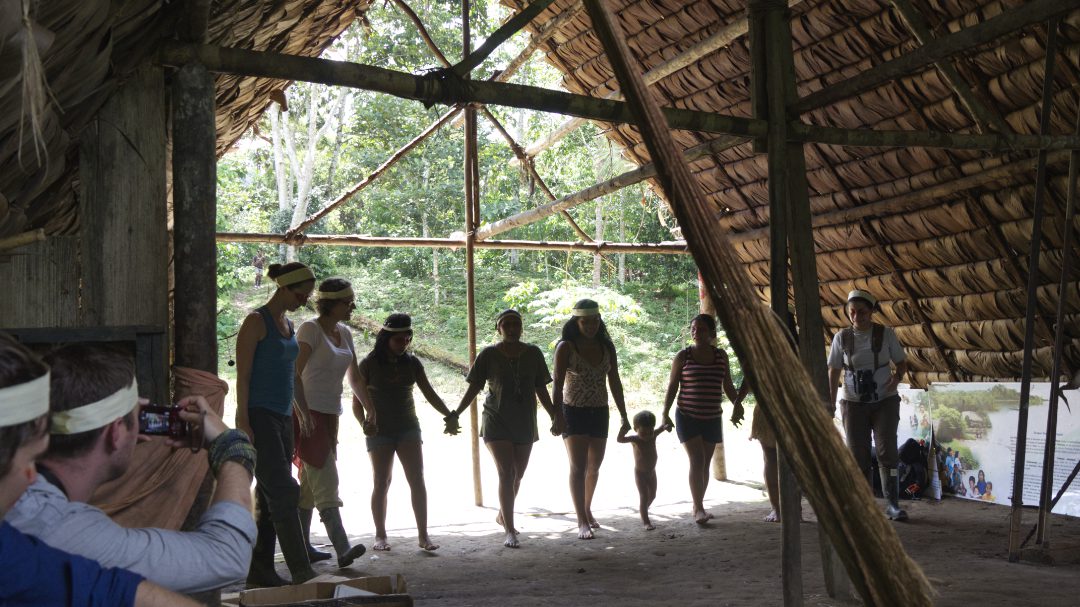 Un grupo de mujeres y niños se toman de la mano en preparación para bailar ante los hombres