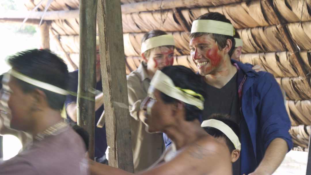 two Huaorani men lead the way as two teenage boys follow in a circular dance