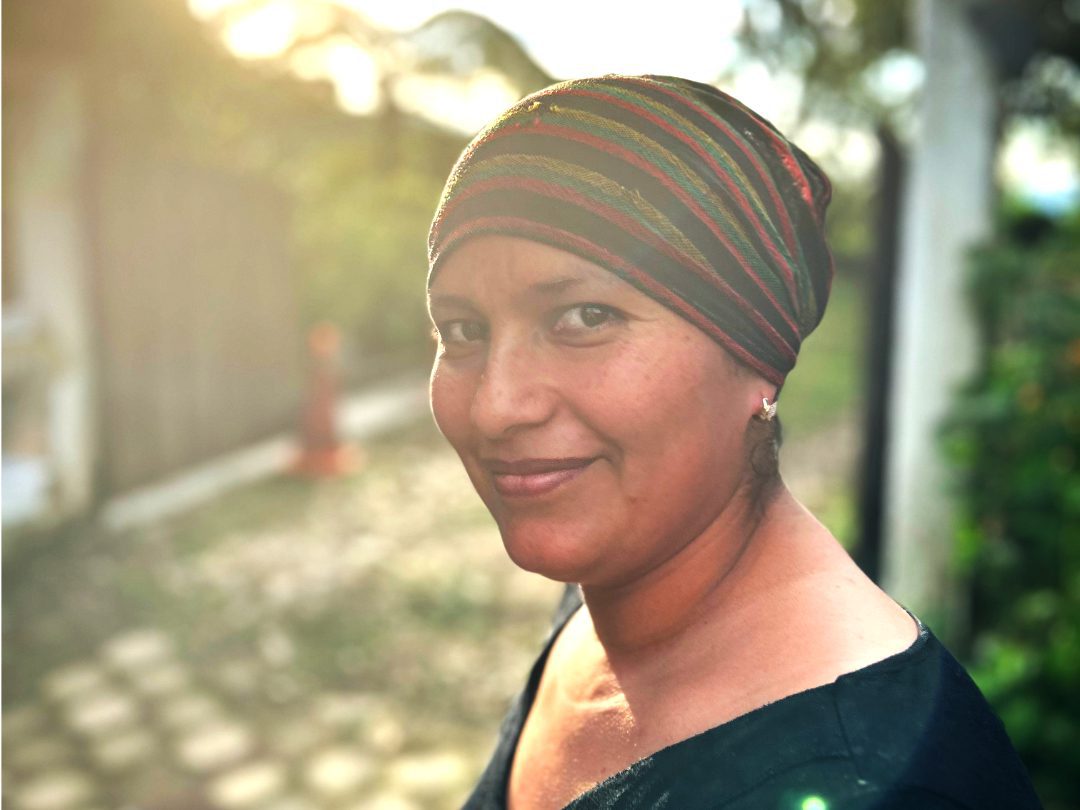 An Ecuadorian woman in a striped cap and black blouse turns to smile at the camera