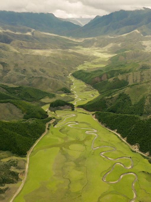 Scenic view of Huaylla Belen, a vast green valley surrounded by mountains in the Chachapoya region, with grazing animals and mist-covered peaks in the distance.