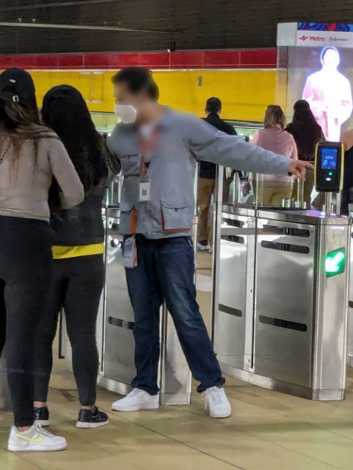 A Quito Metro staff members helps riders with a problem at the entrance gate