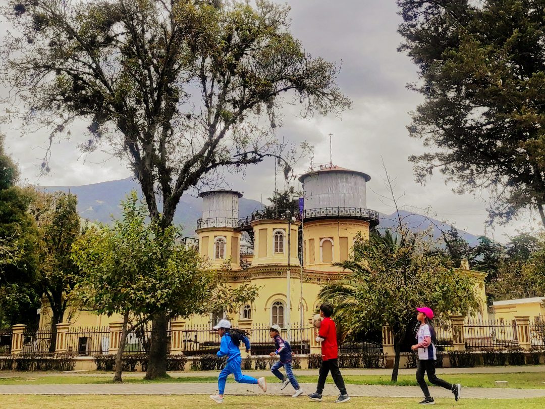 Niños jugando en el Parque La Alameda, el observatorio en el fondo