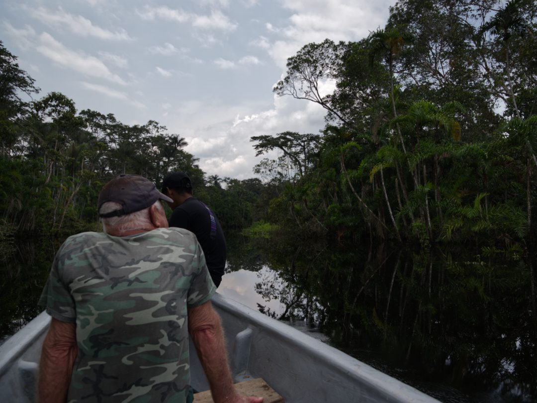 A man sits in a fiberglass canoe, contemplating silence as the boat is paddled by hand | ©Angela Drake