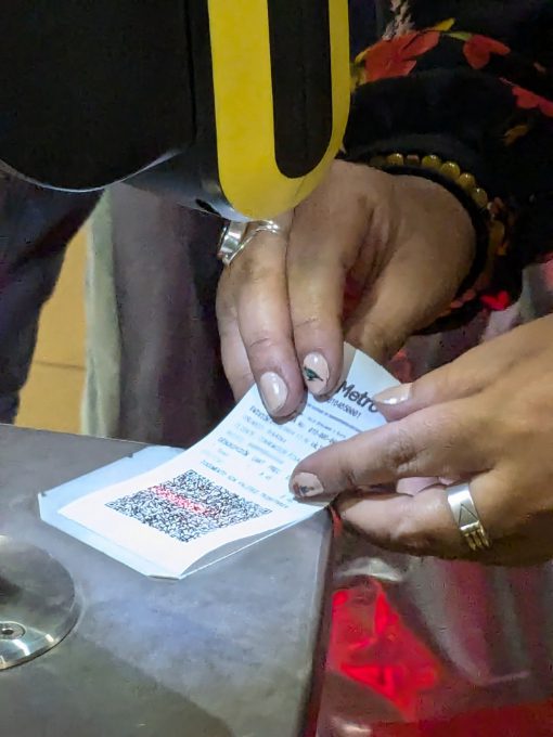 A close up look of a person holding a flimsy, white receipt with scan code under a scanner