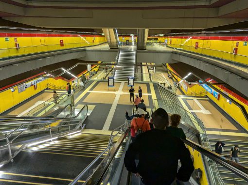 From the escalator, it is possible to see all three levels of the interior of Quito's Metro System: the vestibule across the way, the mezzanine at the base of the escalator, and the tracks on the ground floor