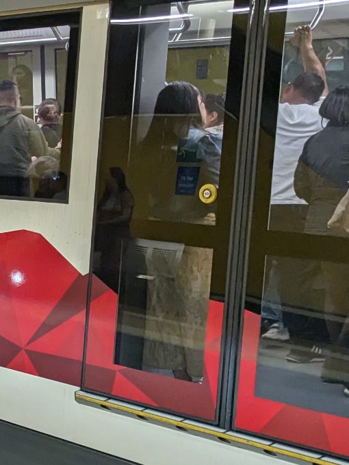 A bright yellow button on a clear glass door of a train car