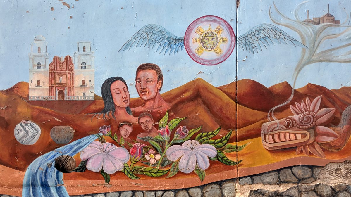 A mural in Tucson's Barrio Viejo shows new growth springing from the desert floor, a family of four portrayed against a background of rust red hills and a mission church