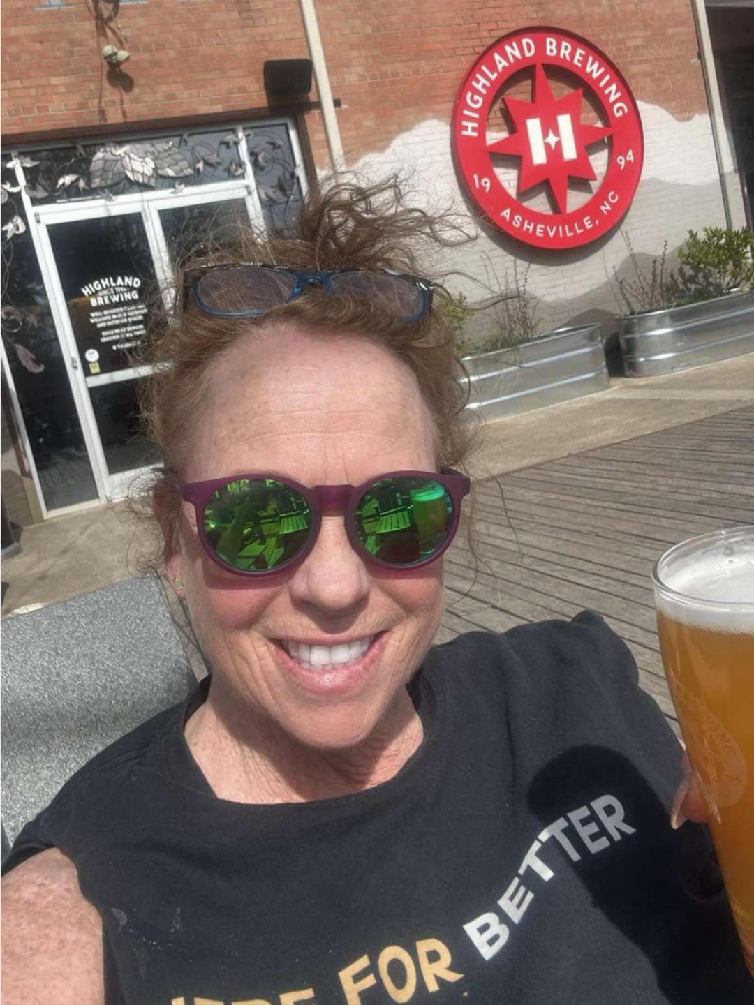 Linda at Highland Brewing A woman in sunglasses holds a tall beer in front of Highland Brewing in Asheville, North Carolina