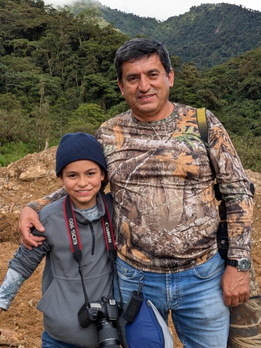 Angel and his son, Lucas A father poses with his arm around his young son with hills and forest in the background