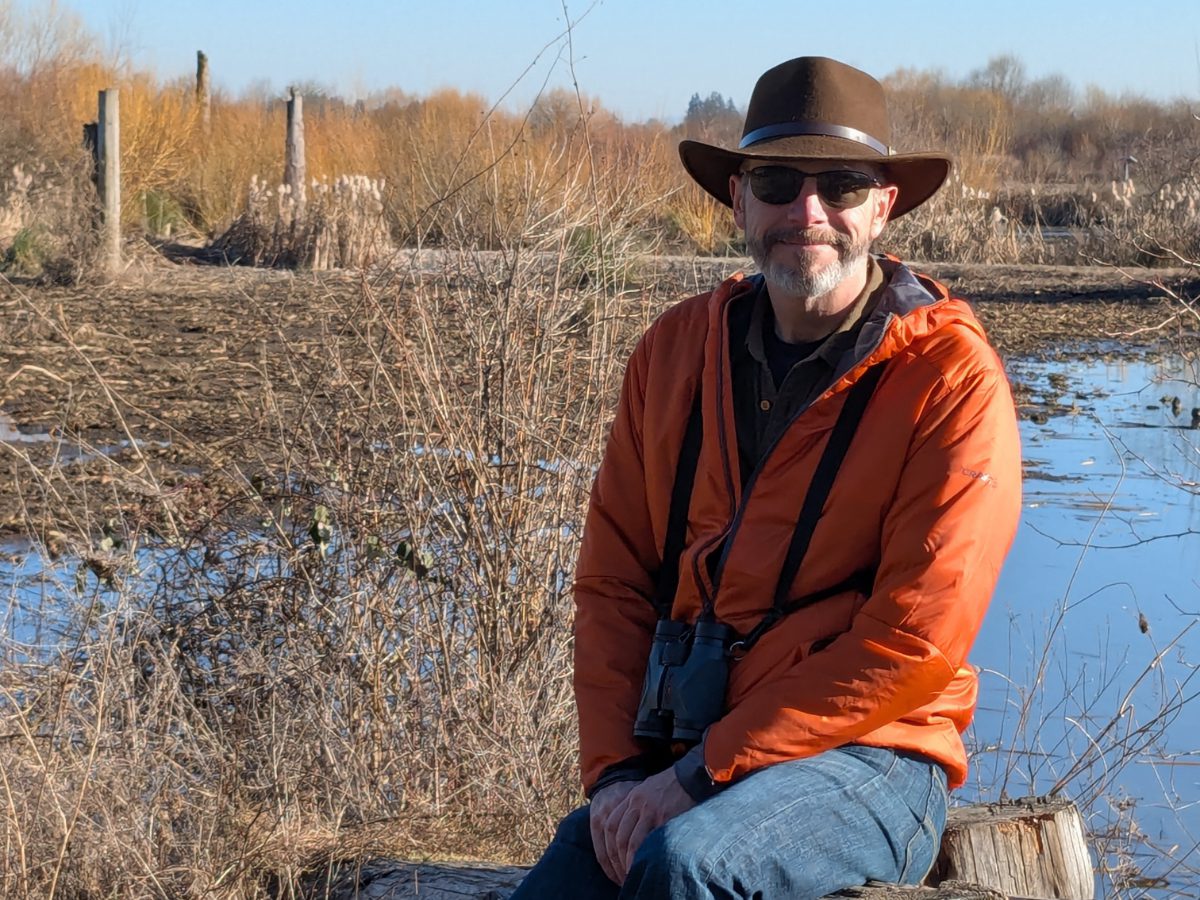Scott wearing a bright orange Craft Sportswear Men's ADV Explore Lightweight Jacket while birdwatching at Fernhill Wetlands in Forest Grove, Oregon
