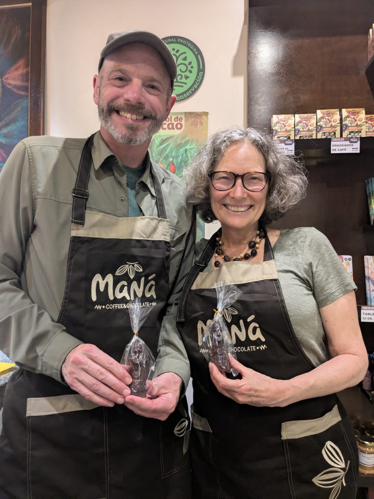 Scott and Angie in their Maná Coffee and Chocolate aprons hold their newly minted chocolate bars, shaped like small Chachapoyas Sarcophagi. 