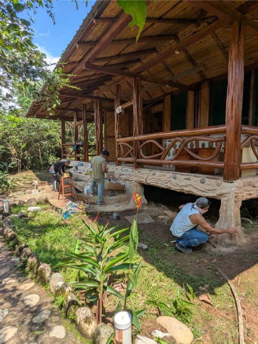 Three craftsmen are touching up details on the family cabin at Ama EcoLodge