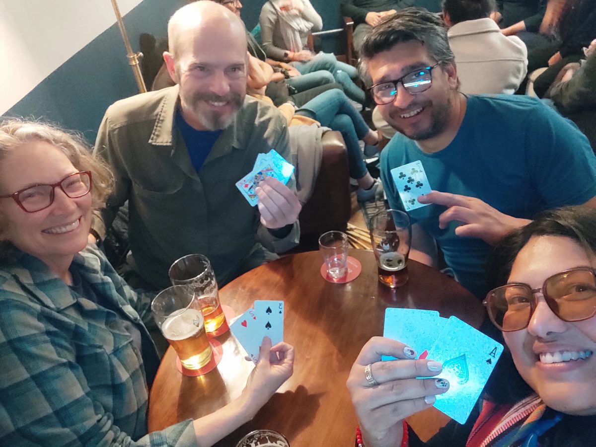 Four people playing cuarenta en a local brewery