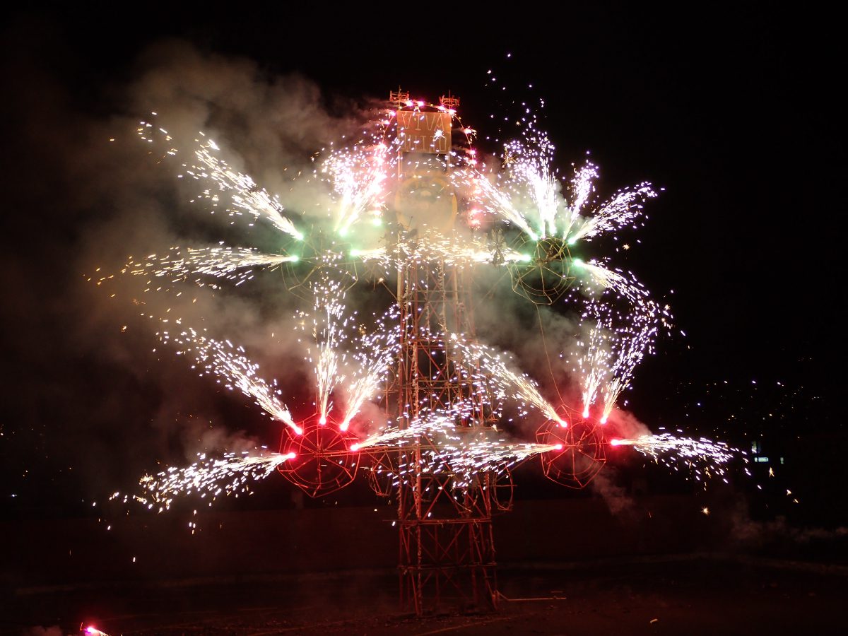 A tower of fireworks, known as el castillo, in full form with four pinwheels spinning with exploding fireworks