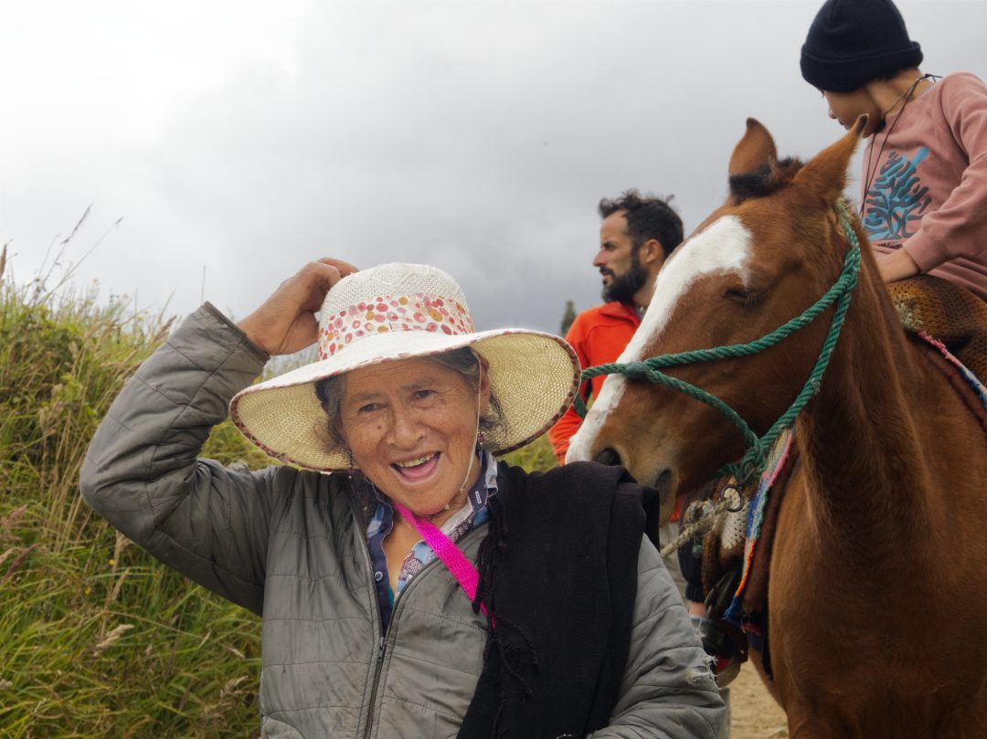 A woman from the community leading a saddled horse with a visitor riding toward the Karajía sarcophagi.