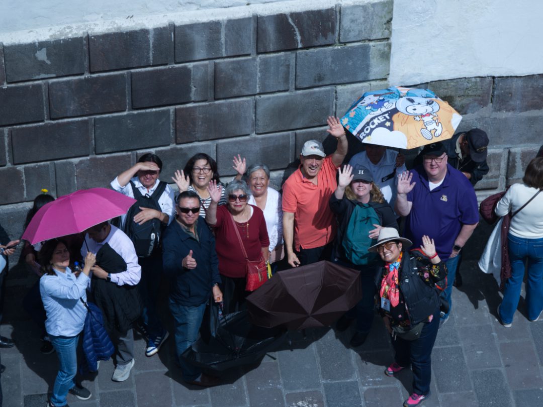A group of people waiting for the Arrastre de Caudas wave up at the photographer.