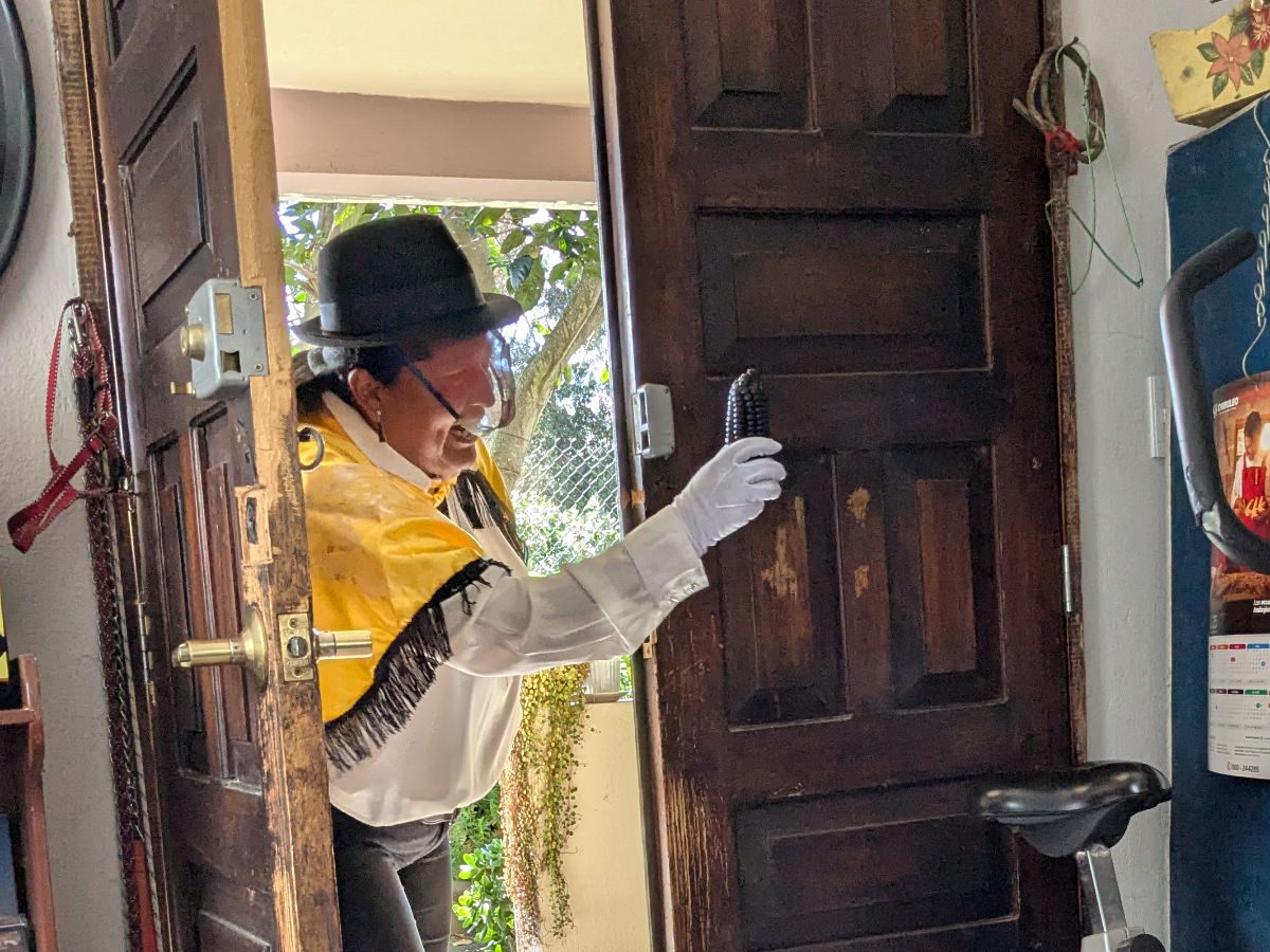 Isabela dressed as a Ruku with yellow cape and black cap, walks into the house