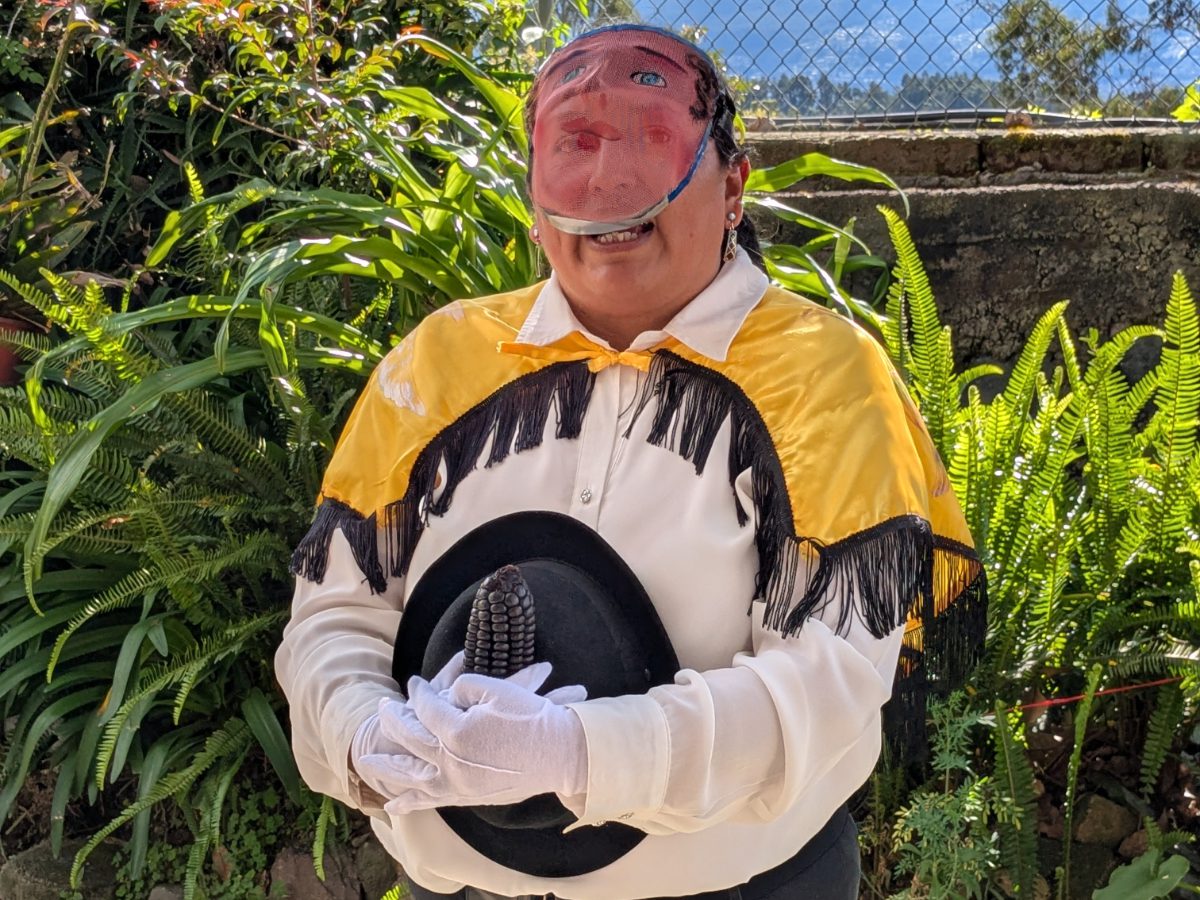 María Isabela dressed in a yellow cape, white shirt, and traditional mask of the a Ruku, a figure important to Alangasi celebrations.
