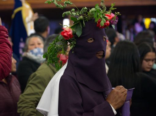 An Alangasí Cucurucho wears roses atop his mask and robes.