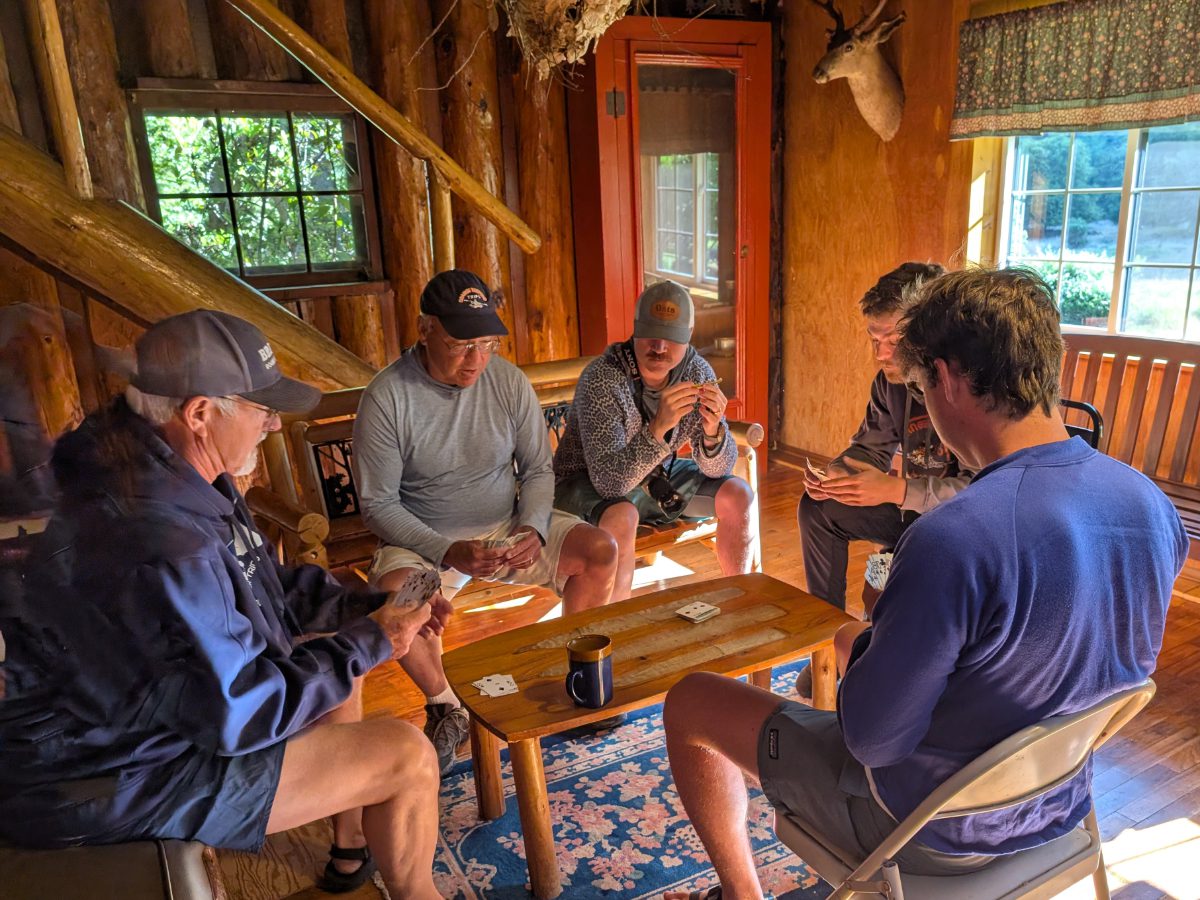 Orange Torpedo Tours Rafting Guides play cribbage while a guest looks on.