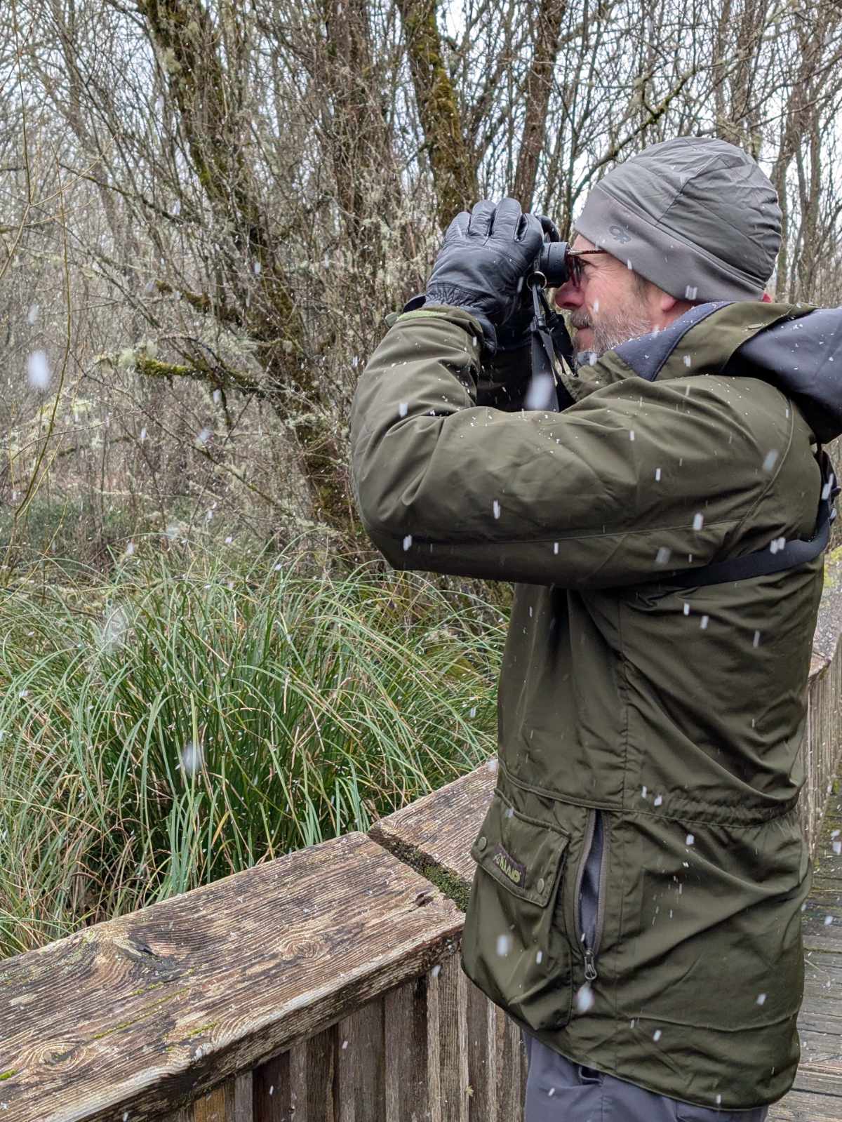 Scott wearing a Paramo Halkon raincoat in damp and snowy conditions while birdwatching.