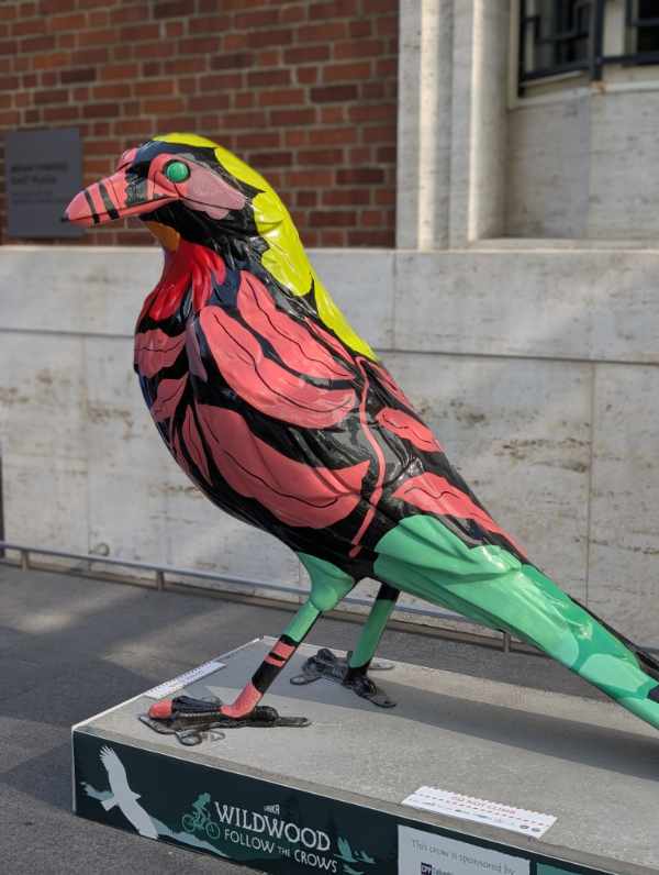 The crow sculpture Bloom is painted in bold oversized botanical print against a deep black background.