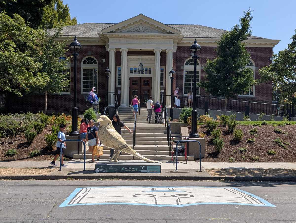 The St Johns Library with a crow statue on the sidewalk in front of the steps leading to the front entrance.