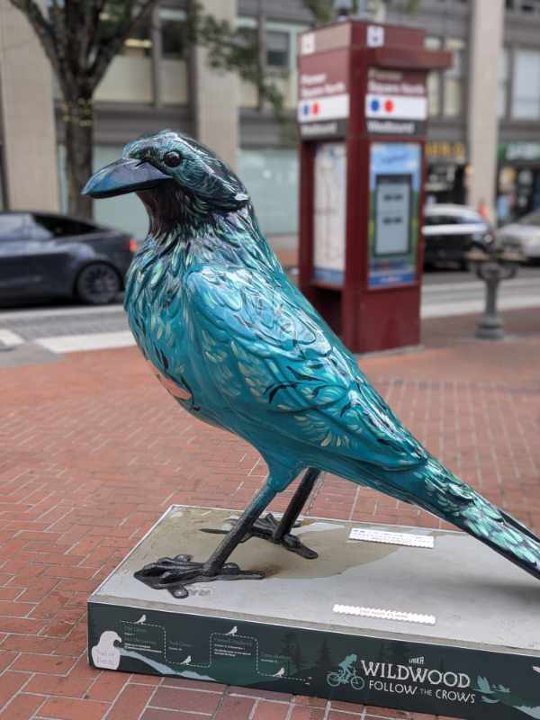 A full-body shot of the crow statue, Overgrowth, at Pioneer Plaza in Portland, oregon