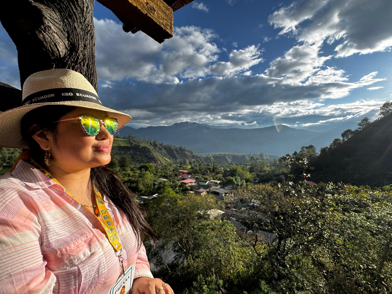 La autora, Jacqueline Granda, posa con gafas de sol y sombrero panamá mientras contempla un paisaje rural bañado de sol en el sur de Colombia, en Nariño.