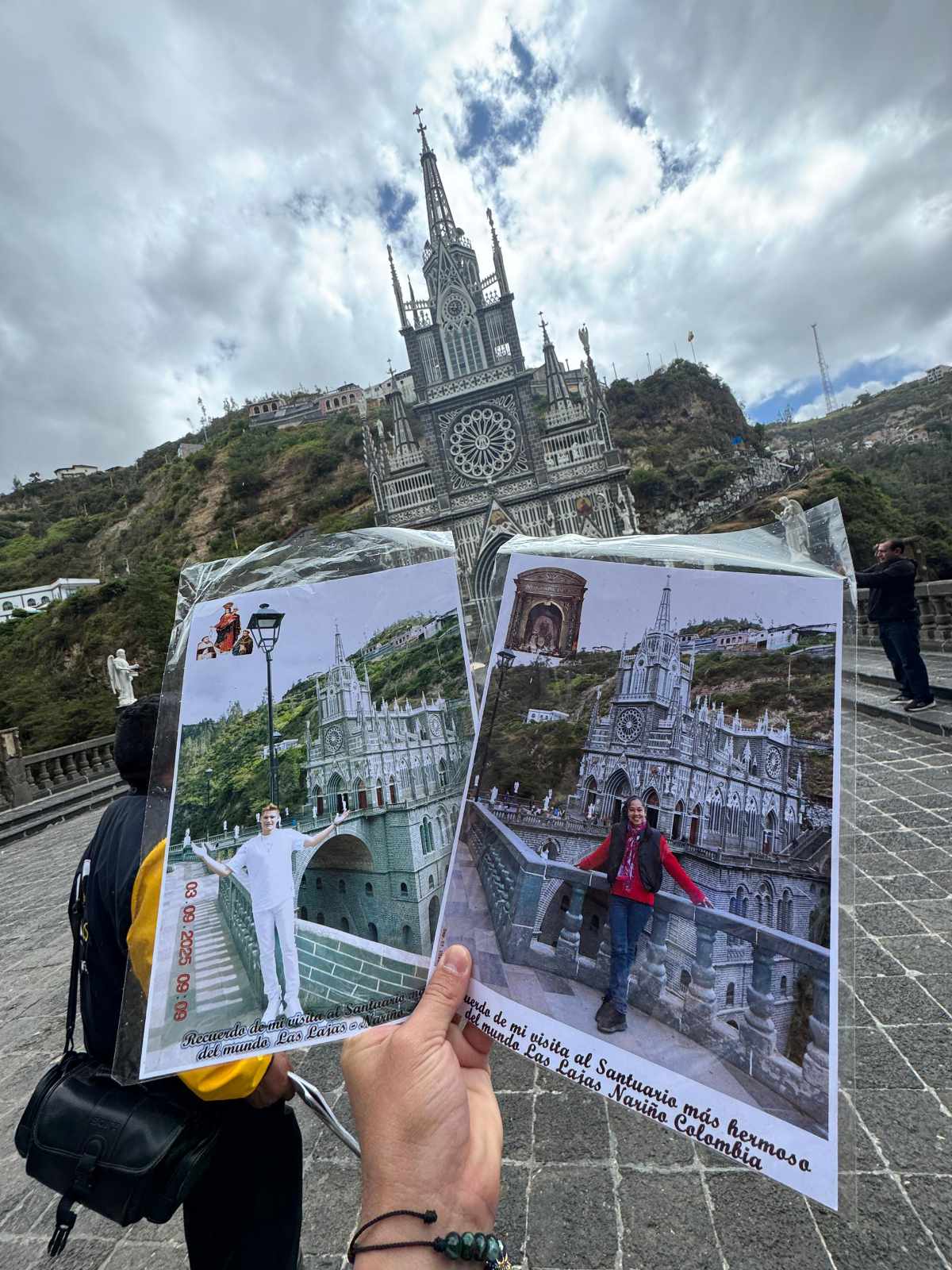 Alguien sostiene dos imágenes del Santuario de Las Lajas, cada una con un turista distinto posando, con la iglesia real de fondo.