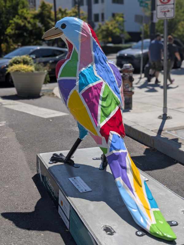 The back side of the Shape of Us crow sculpture shows triangular shapes of color spilling down the bird's back and tail. 