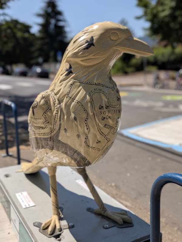 A close-up shot of the front of the World of Wildwood Crow, showing its head and beak in profile.