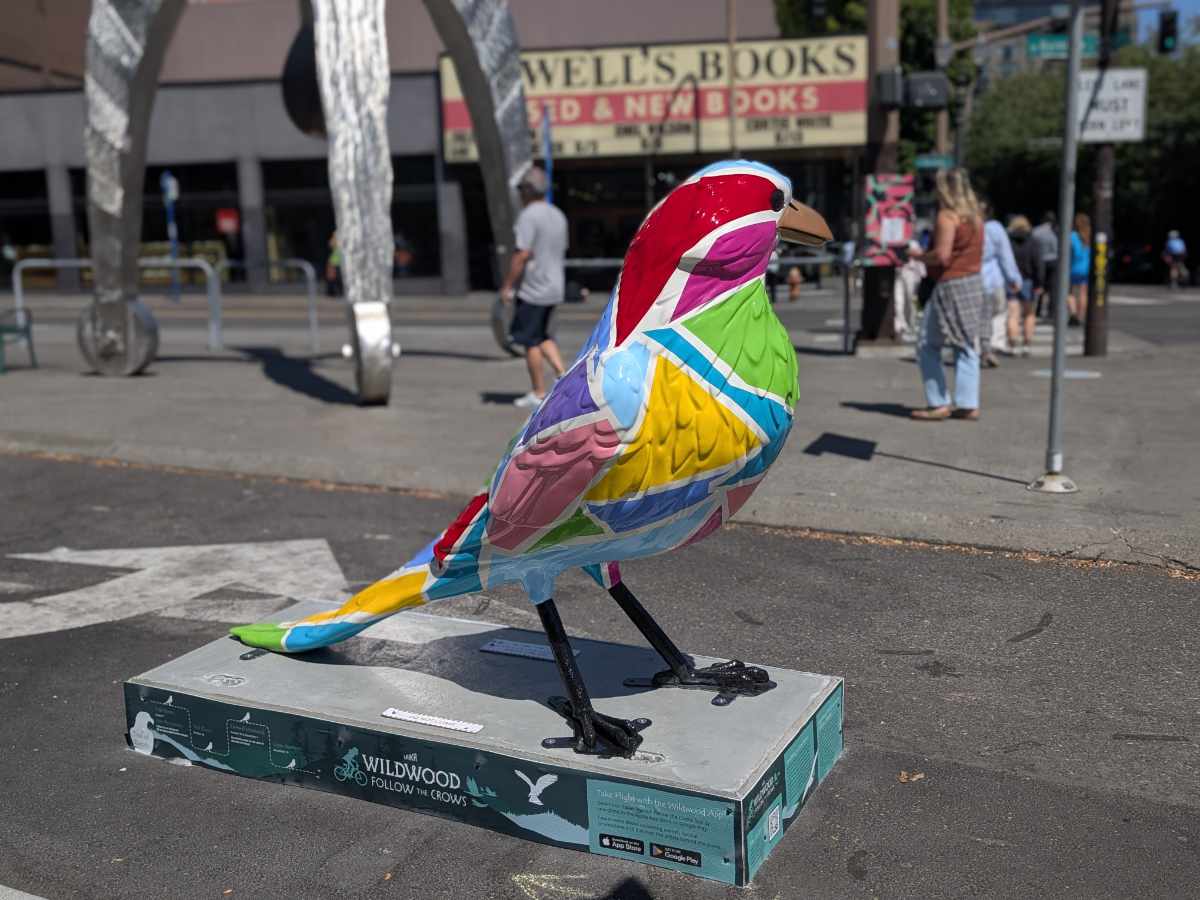 A crow statue pained with blocks of vibrant jewel tones and white lines stands across the street from Powell's Books in Portland, Oregon